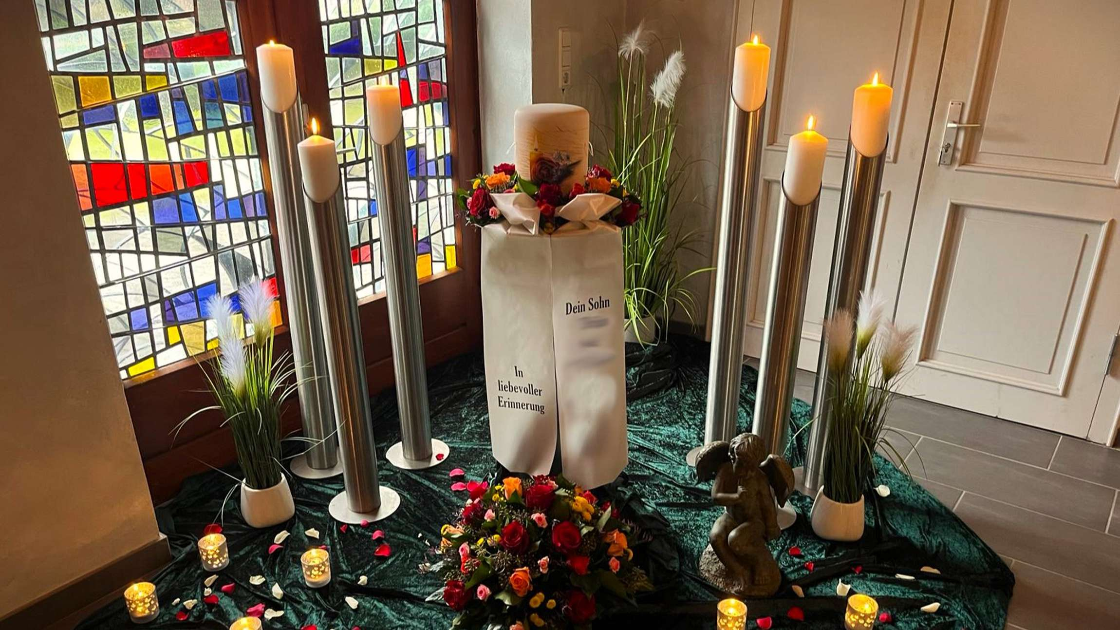 Altar mit Kerzen und Urne auf Podest