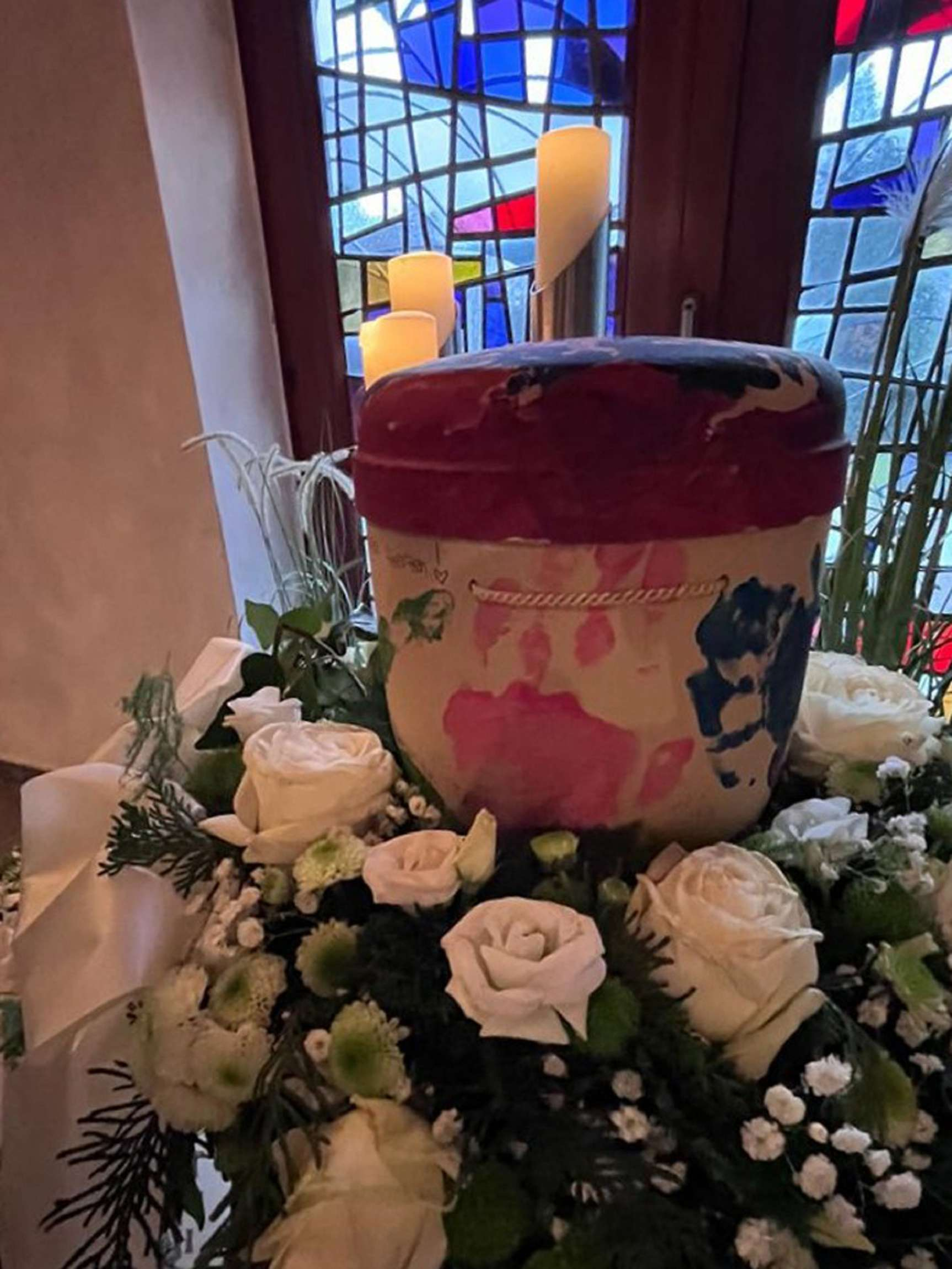 Schmuckurne steht auf Blumenkranz